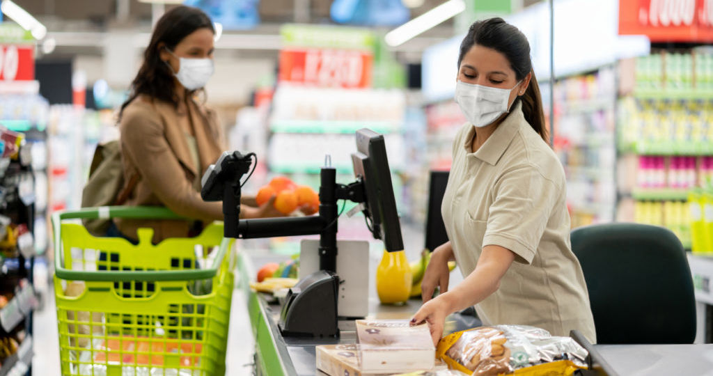Cashier scanning products at a grocery store wearing a facemask